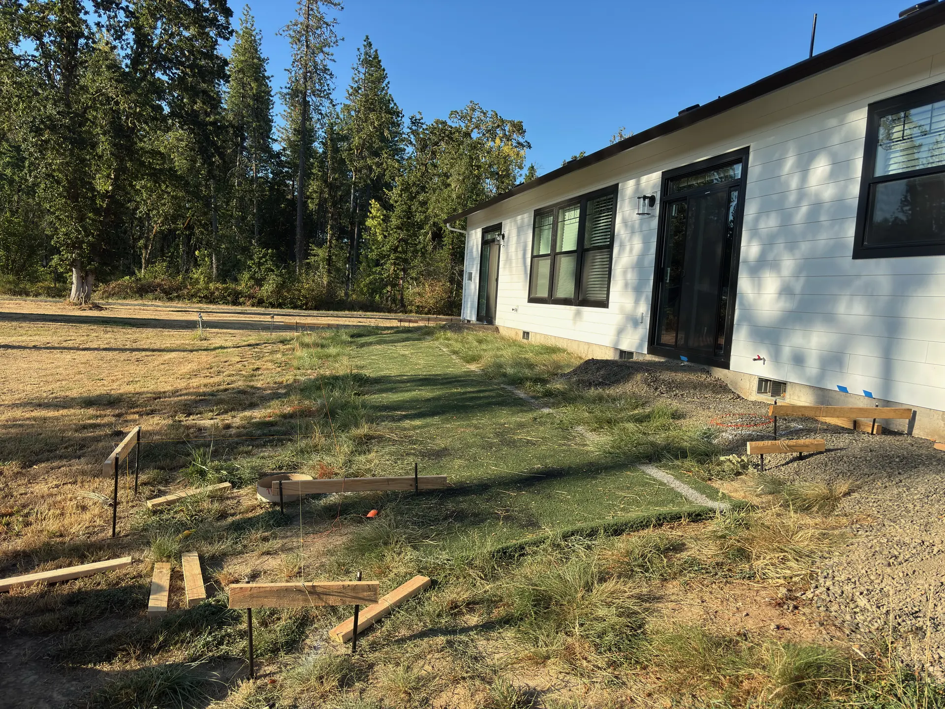 Deck planning checklist in practice: layout stakes and batter boards set before a Tekton deck build in Elmira, Oregon