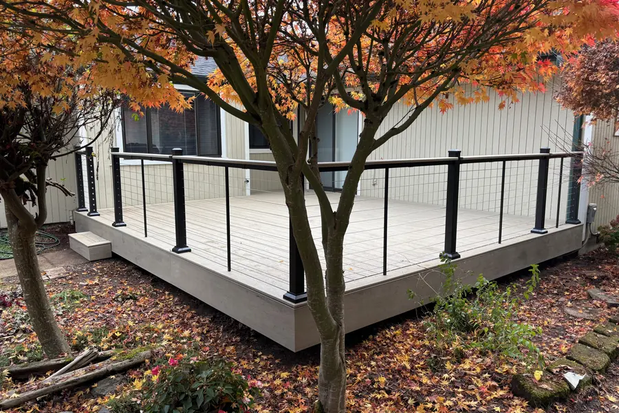 Composite deck with black cable railing under a Japanese maple in autumn, Springfield Oregon
