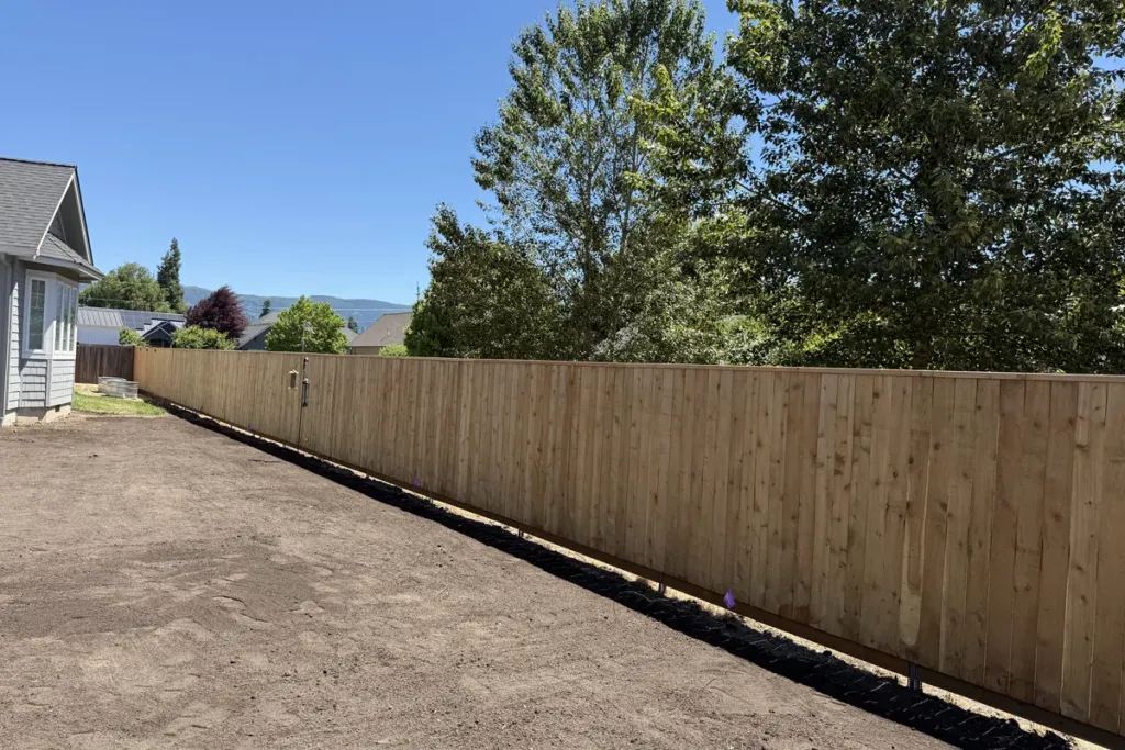 Finished cedar privacy fence with capped top rail and black post caps