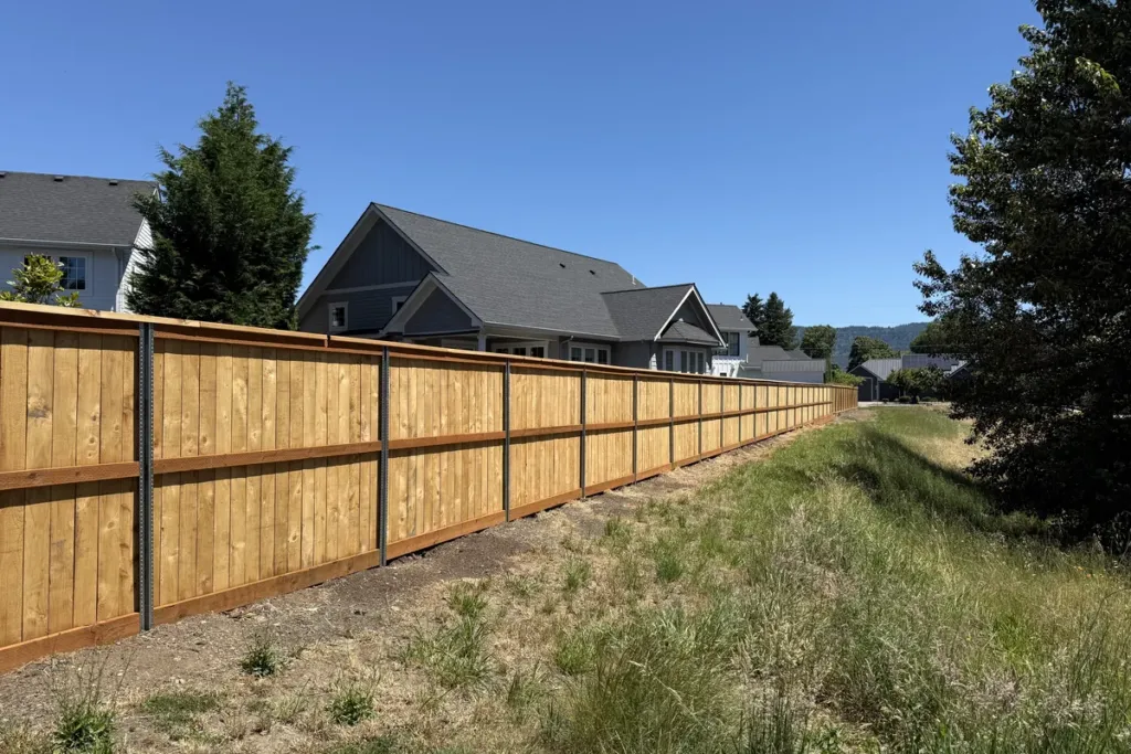 Long cedar fence run with a capped top rail looking out over open ground