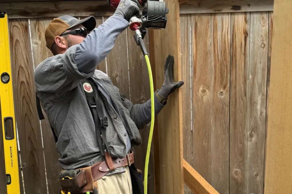 Tekton Construction crew member nailing cedar fence rails into place
