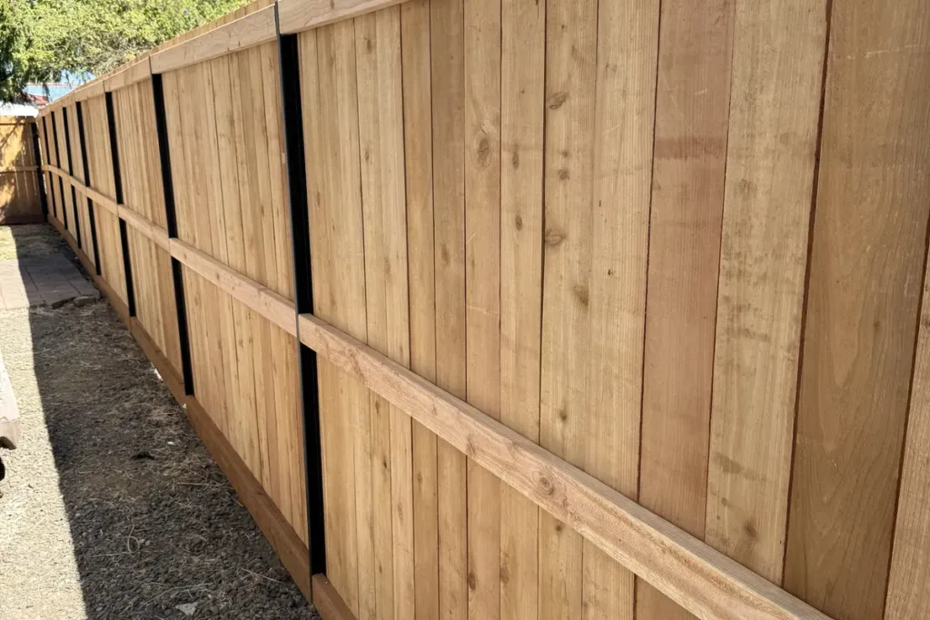 Cedar privacy fence with black steel posts running the length of a back garden