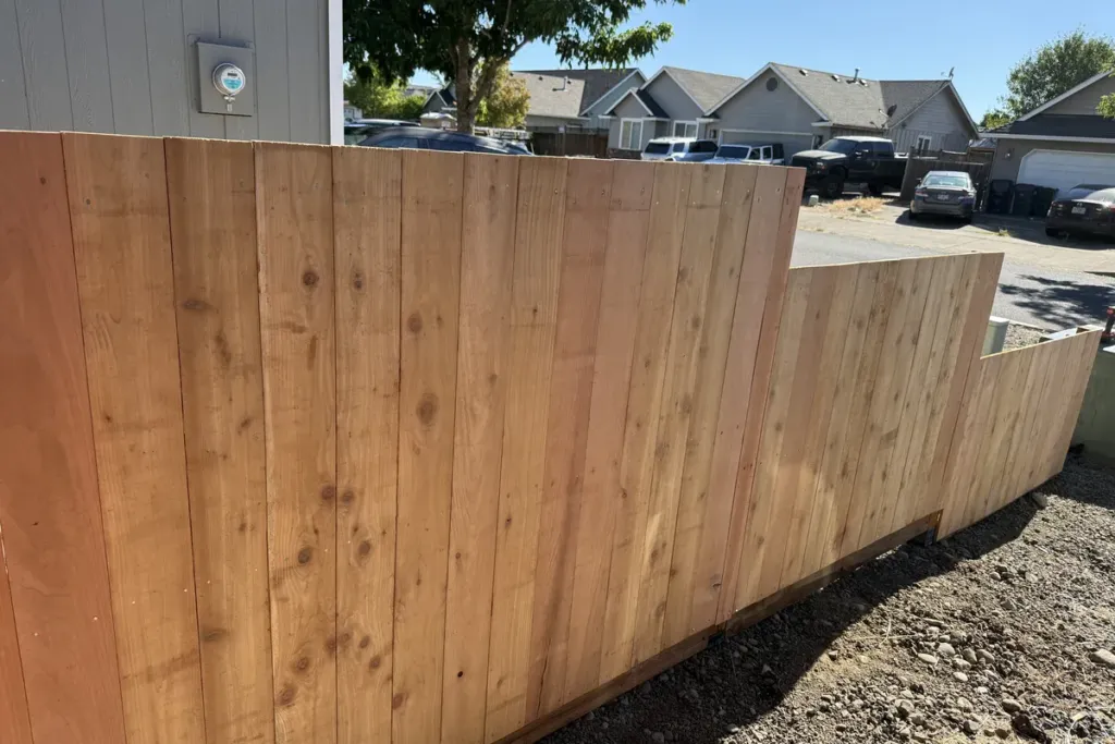 Cedar privacy fence stepped down a sloping grade with a level top line