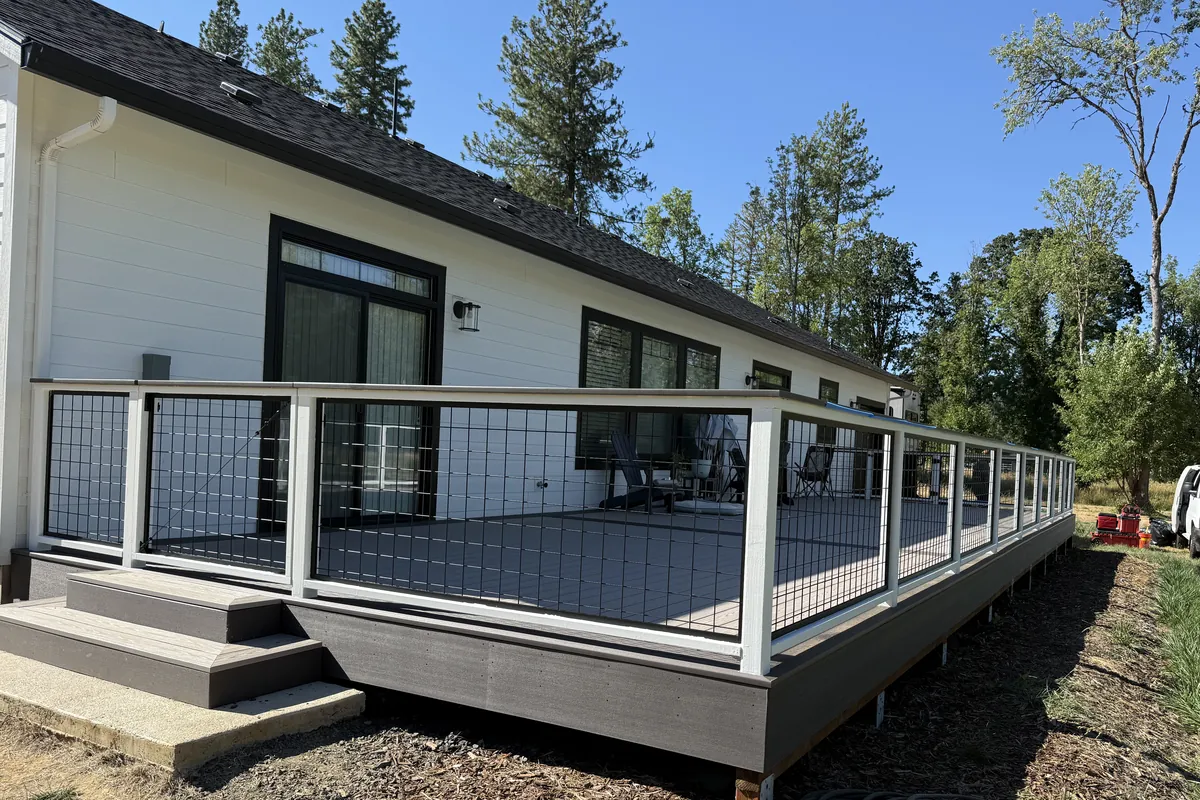 Composite deck with white posts and black wire panel railing built by Tekton Construction, a deck and fence contractor in Eugene, Oregon