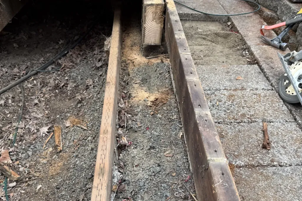 Deck framing and joists under a patio cover before composite boards are fitted